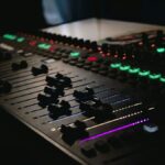 Beleuchtetes Mischpult mit Reglern und farbigen Tasten im dunklen Studio