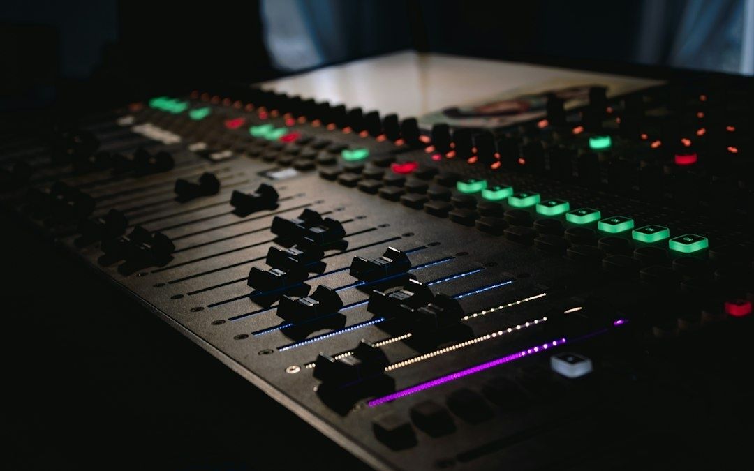 Beleuchtetes Mischpult mit Reglern und farbigen Tasten im dunklen Studio