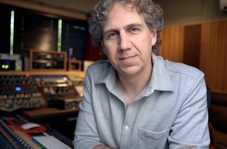 Mann in einem Tonstudio vor analoger Audiotechnik und Mischpult