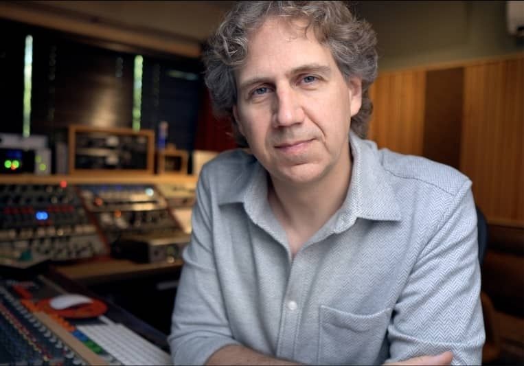 Mann in einem Tonstudio vor analoger Audiotechnik und Mischpult