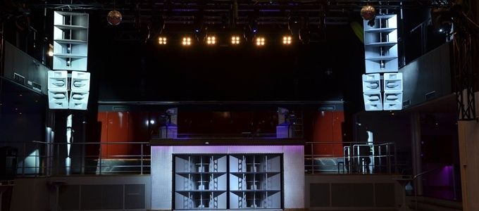 Dunkler Clubraum mit Lautsprechertürmen, DJ-Pult und Bühnenlicht